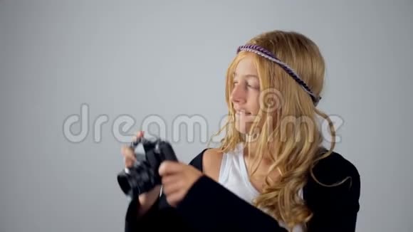一个可爱的金发女孩手里拿着灰色背景的相机视频的预览图