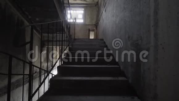 在黑暗中爬上恐怖的楼梯一个人在恐怖的楼梯间爬上黑暗而危险的楼梯慢动作视频的预览图