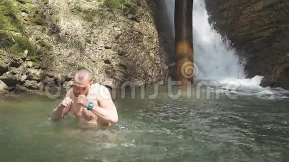 游客在岩石山上的湖里洗澡徒步旅行很长一段时间后使自己精神焕发视频的预览图