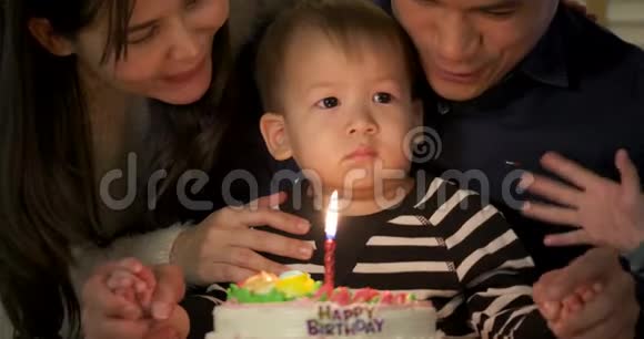 一个可爱的小男孩坐在桌子旁在生日蛋糕上吹蜡烛动作缓慢视频的预览图
