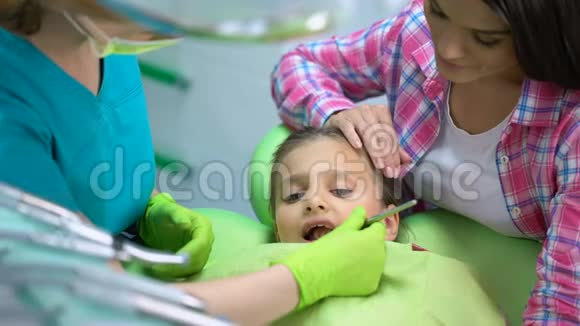 小女孩定期做牙齿检查妈妈抱着女儿镇静下来视频的预览图