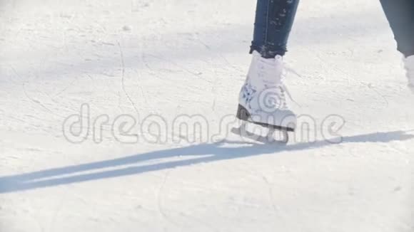 一个年轻女孩的腿熟练地在户外公共冰场滑冰慢动作视频的预览图