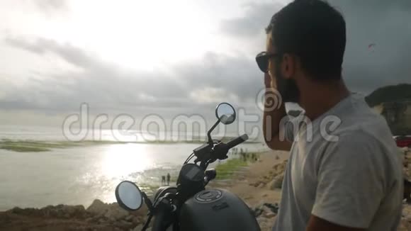 年轻人骑摩托车停在海边视频的预览图