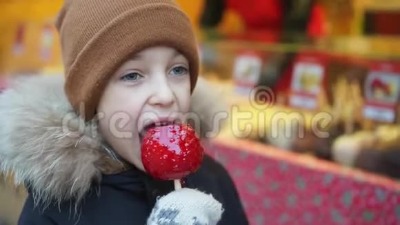男孩在圣诞节市场上咬了一个焦糖苹果视频的预览图