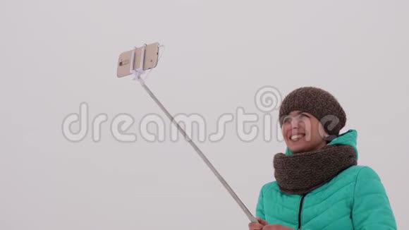 女孩在智能手机和自拍上拍照在冬季公园在圣诞节早上快乐的女孩走在雪地里视频的预览图
