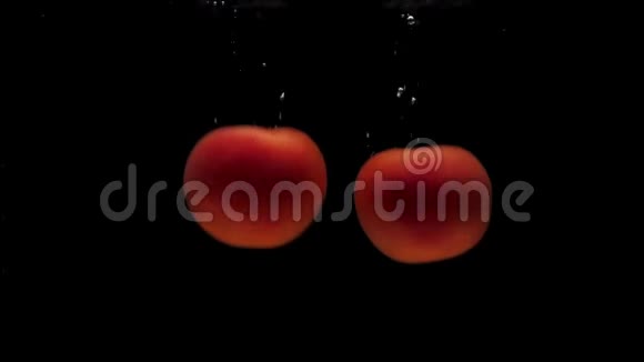 两个红色的假名在黑色的背景下落入透明的水中视频的预览图