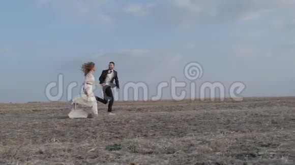 快乐的年轻夫妇牵着手穿过一片广阔的田野在户外玩得很开心乡村男人和女人在奔跑视频的预览图