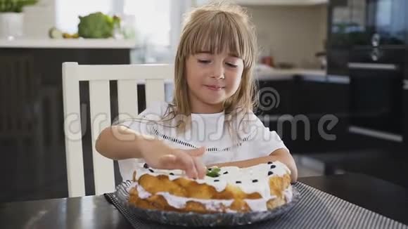 一个可爱的小女孩在家吃新鲜甜蛋糕的肖像白衣长发美女视频的预览图