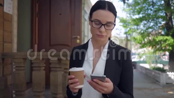 沮丧的商务女士一边用手机边走边喝咖啡视频的预览图