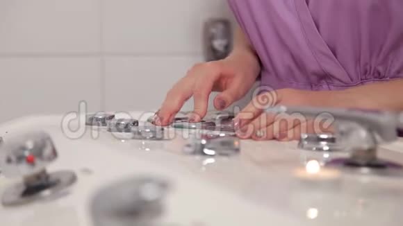 女孩水疗沙龙工作人员调节热水进入浴缸的流量视频的预览图