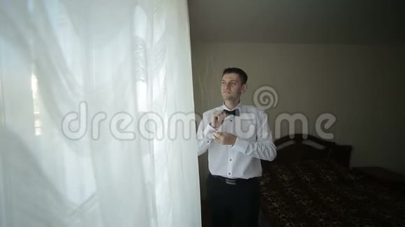 穿白色衬衫的人在窗户附近系蝴蝶结视频的预览图