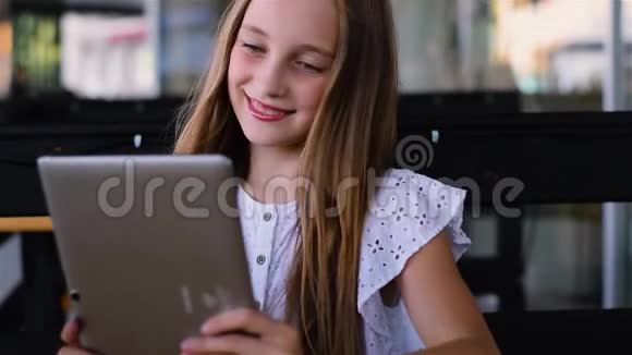 小女孩在咖啡馆里用平板电脑微笑着视频的预览图