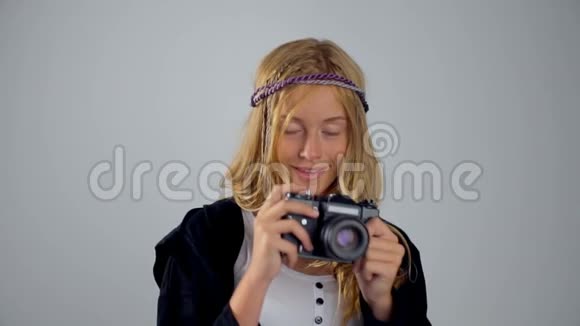 一个可爱的金发女孩手里拿着灰色背景的相机视频的预览图
