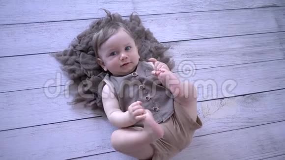 婴儿生活可爱的婴儿躺在木地板上拉腿视频的预览图