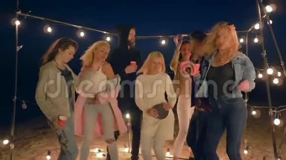 海派对一群朋友跳舞在沙滩上享受灯光下的休息视频的预览图