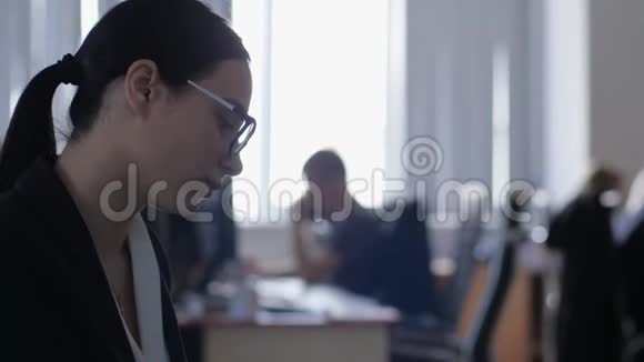 精疲力竭的女商人带着手机坐在办公室特写的工作场所后面视频的预览图
