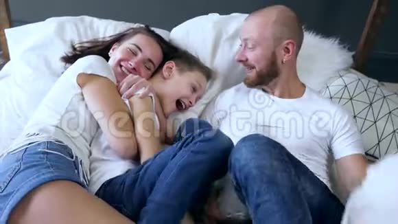 父母和他们的孩子带着枕头在床上玩耍和欢笑幸福的家庭时刻视频的预览图