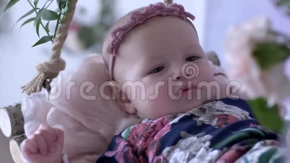 孩子平安可爱的宝宝头上戴着时髦的花环在房间里荡秋千视频的预览图