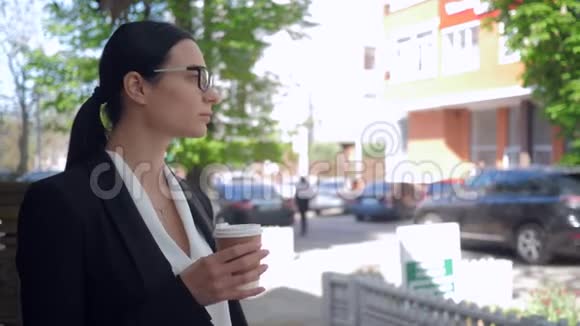 患有抑郁症严肃的女商人喝咖啡在城市街道上持有现代智能手机视频的预览图