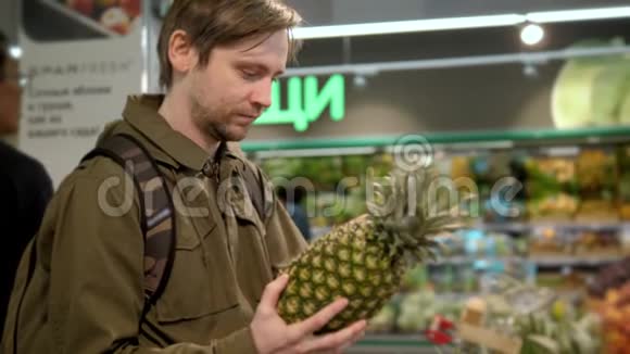 男人手从食物架上拿了一个新鲜的菠萝有机产品蔬菜和水果健康食品购物视频的预览图