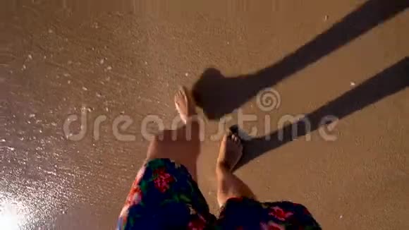 人在海滩上散步海浪洗他的腿视频的预览图