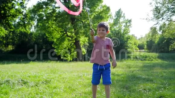 快乐的童年可爱的孩子在绿色的草地上用粉红色的丝带玩耍视频的预览图