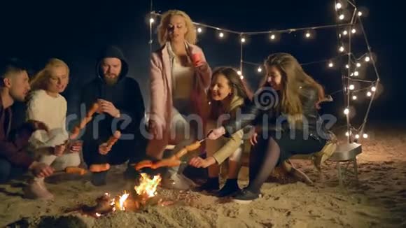 海滩野餐朋友的陪伴在沙滩海岸烤香肠在晚上视频的预览图