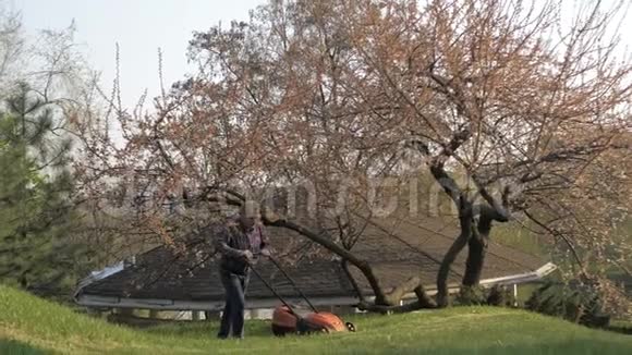 成年男子电动割草机割草机园丁修剪花园视频的预览图