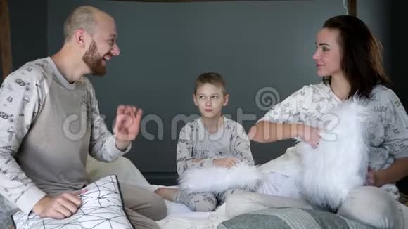 快乐的家庭时刻男孩和他们年轻的父母在房间的床上玩有趣的特写镜头视频的预览图