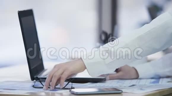 自信的女人戴着眼镜在笔记本电脑上工作在办公室喝茶视频的预览图