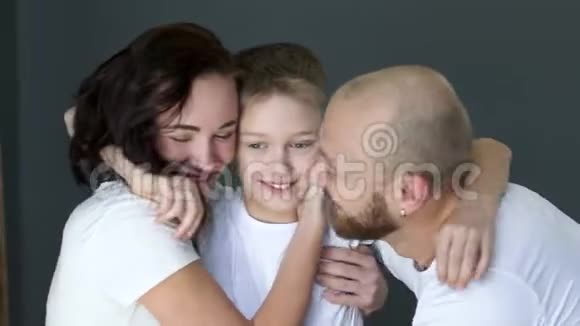 男孩紧紧拥抱年轻的父母一家人在摄影棚里一起玩视频的预览图