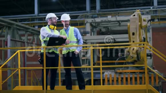 两个工人正在现代化的工厂里谈话视频的预览图