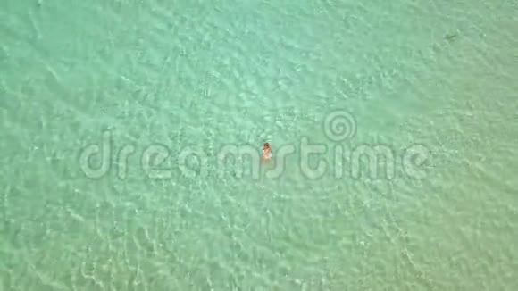 鸟瞰女人在绿松石海水女人在天堂海滩清澈的海水中转身视频的预览图