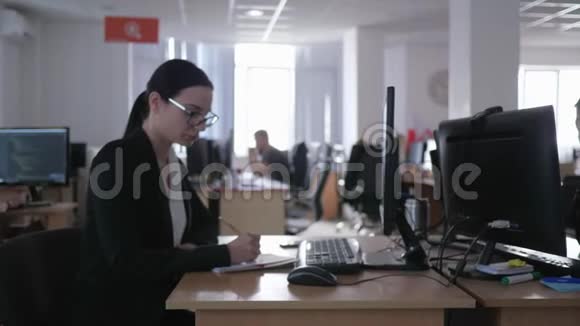 工作不好戴眼镜的女孩皱着眉头在电脑办公室工作在笔记本上做笔记视频的预览图
