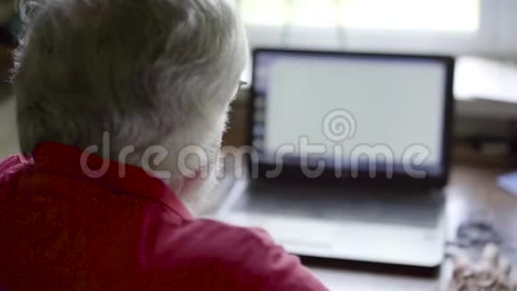 坐在家里的桌子上用笔记本电脑的老人视频的预览图