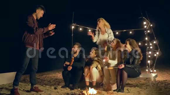 在篝火旁野餐快乐的朋友在海滨的火海边野餐视频的预览图