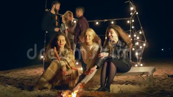 在海滩野餐男孩和女孩在海边篝火旁度过美好时光晚上用灯泡照明视频的预览图