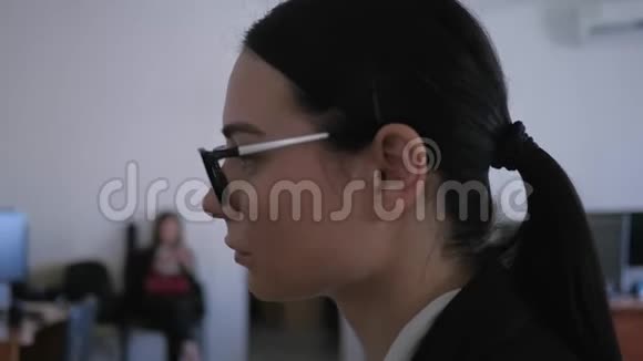 沮丧疲惫的戴着眼镜的女孩在办公室的特写镜头中思考工作场所的一些事情视频的预览图