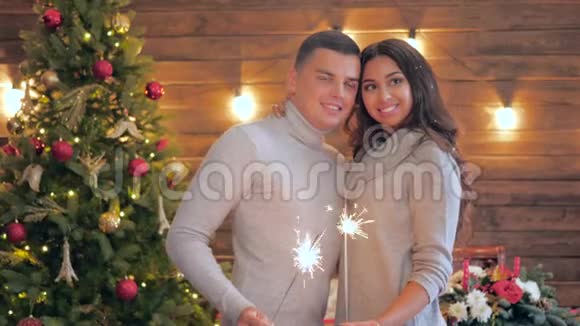 圣诞家庭幸福的年轻夫妇在新年前夕摆姿势与火花合影视频的预览图