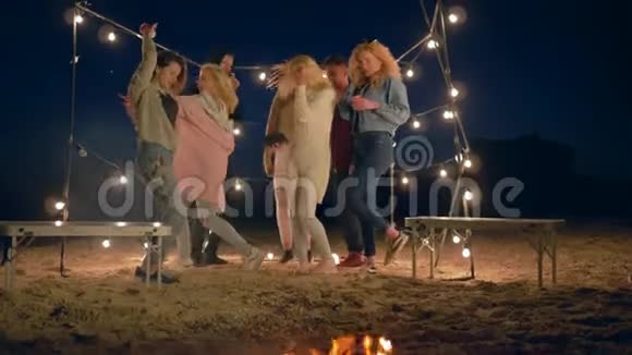 一群跳舞的人在海滩上的篝火旁唱歌在花环的灯光下玩得开心视频的预览图
