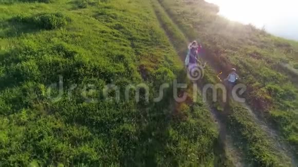 快乐的童年十几岁的妹妹们手里拿着彩带在草地上沿着树枝奔跑视频的预览图