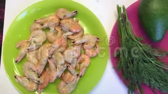 迪尔鳄梨黄瓜和厨房用具躺在桌子表面煮熟的虾躺在盘子里女人在工作视频的预览图
