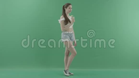 年轻漂亮的女人在绿色背景下摆出鸡尾酒的姿势视频的预览图