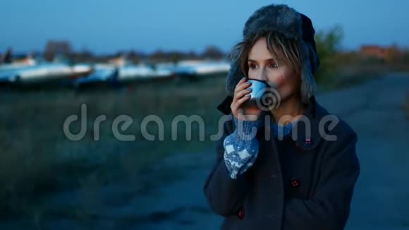 可爱的欧洲年轻女性在日落时在海滩上喝咖啡视频的预览图