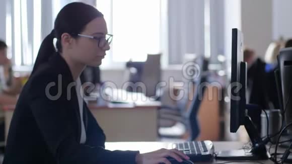 冷漠不开心的女商人戴着眼镜坐在办公室的桌子旁用电脑工作视频的预览图