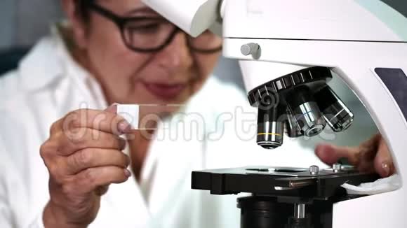 在她的实验室做显微镜的资深女科学家视频的预览图