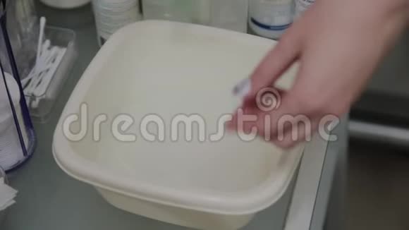 准备湿巾擦拭皮肤的过程把美容师的手举起来白色杯中的水溶液视频的预览图