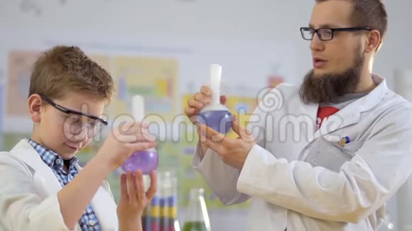 科学家和他的学生手里拿着热气腾腾的彩色液体瓶视频的预览图