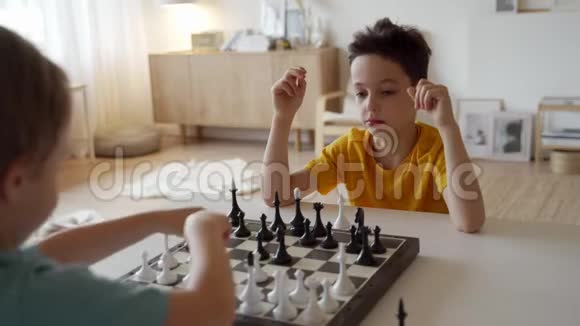 两个男孩在灯光室下棋两个兄弟在下棋视频的预览图
