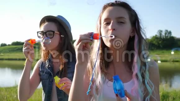 阳光明媚的夏日美丽的微笑女孩青春期的少女在大自然中吹肥皂泡视频的预览图
